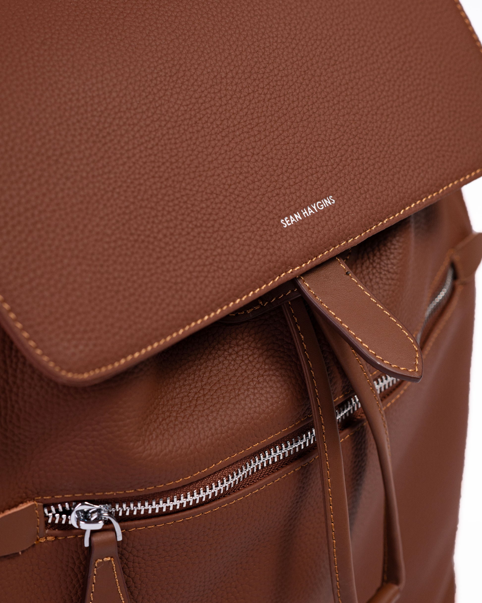 Brown leather backpack with visible brand name on a white background