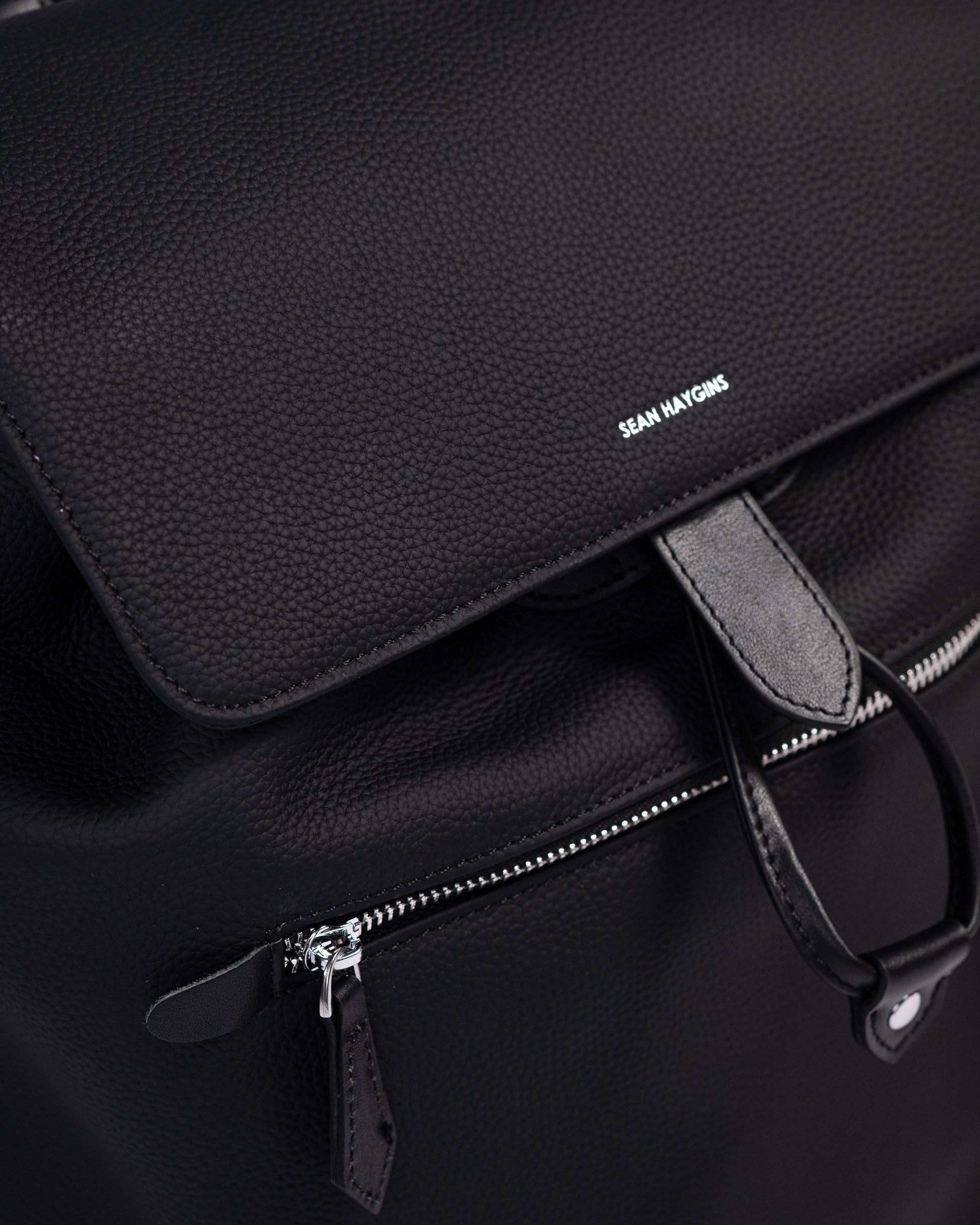 Black leather bag with a visible brand name on a dark background