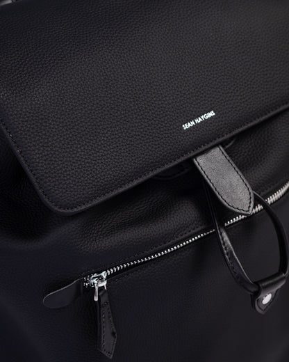 Black leather bag with a visible brand name on a dark background
