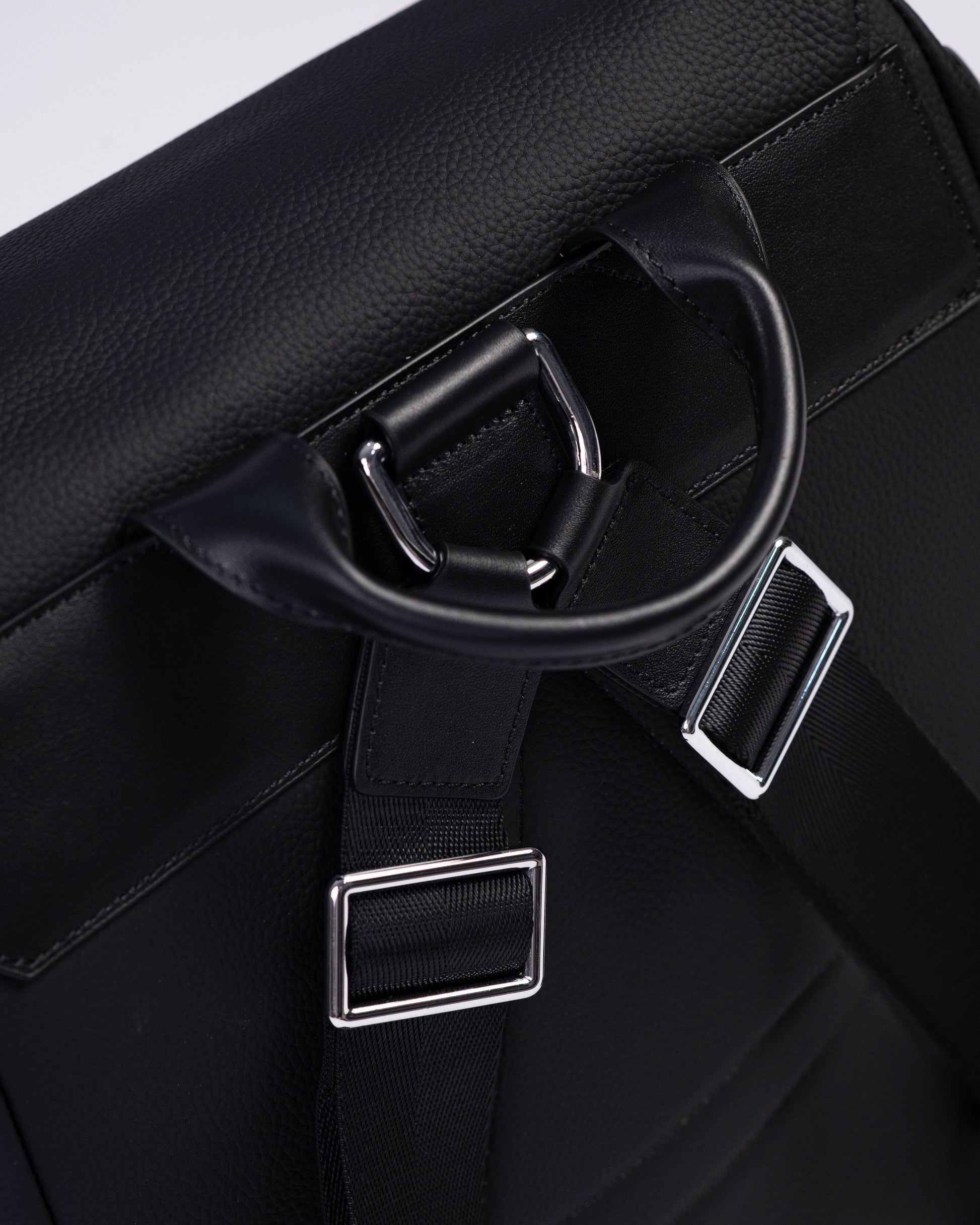 Close-up of a black leather bag with silver hardware on a white background