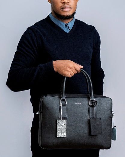 Man holding a black briefcase against a gray background